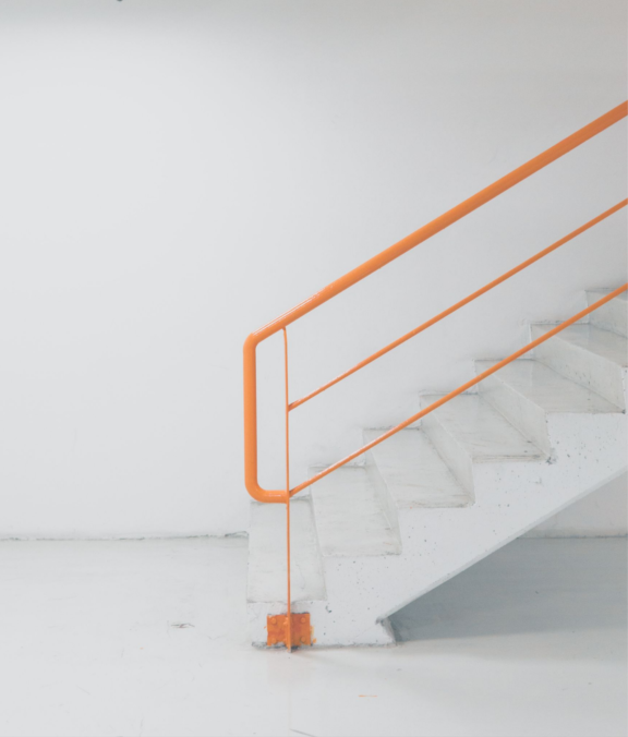 Vit trappa med trappräcke i orange färg