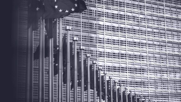 EU byggnad i bakgrunden med EU flaggor framför